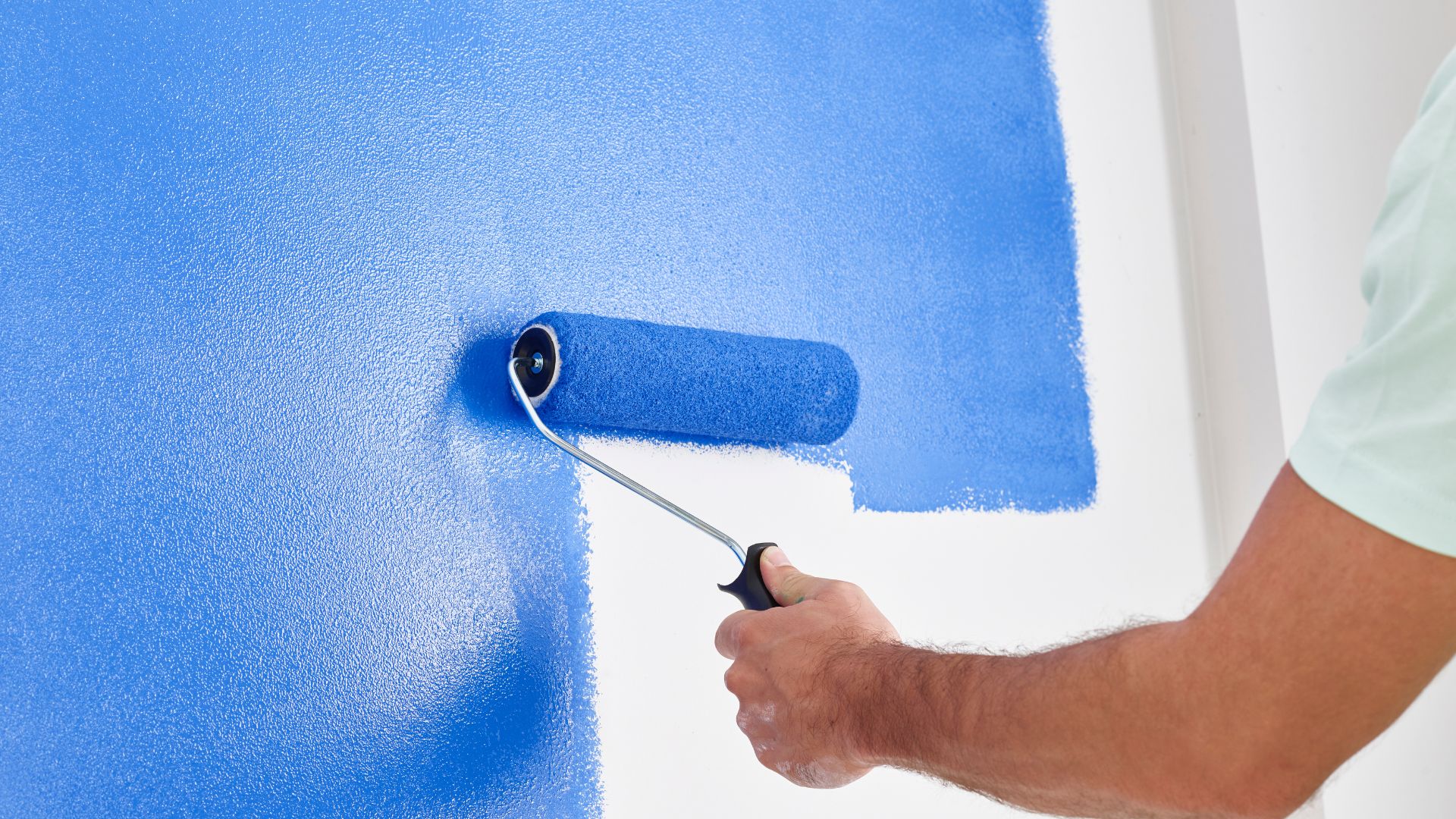 Close view of blue paint being applied with a roller